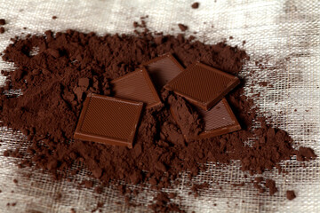 Top view with cocoa powder and delicious chocolate on wooden background