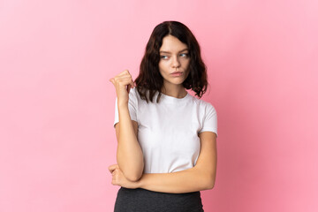 Teenager Ukrainian girl isolated on pink background unhappy and pointing to the side