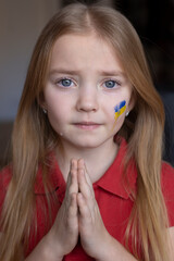 the face of a frightened girl, a child crying, tears flowing, painted on her cheek in the...