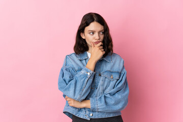 Teenager Ukrainian girl isolated on pink background having doubts and with confuse face expression