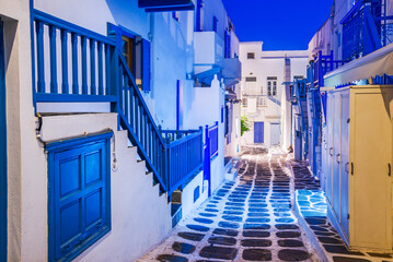 Mykonos, Greece - Cobblestone alley whitewashed village Cyclades Islands night view - obrazy, fototapety, plakaty