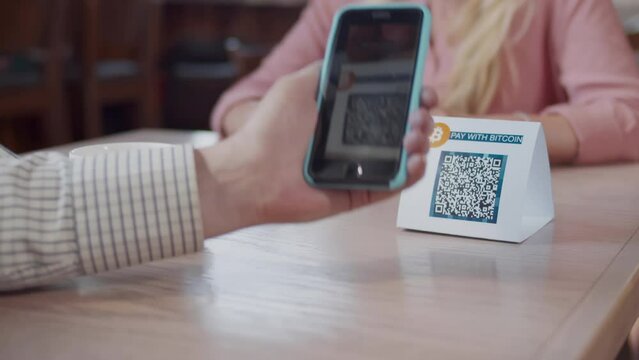 Cropped shot of man scan qr-code with smartphone in restaurant to pay. Realtime