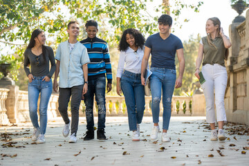 A row of young multiracial group of students walking together outdoors