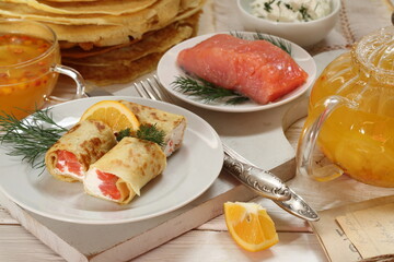Pancakes with salmon, cream cheese and red caviar on a white background