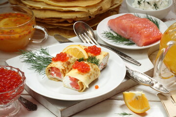 Pancakes with salmon, cream cheese and red caviar on a white background