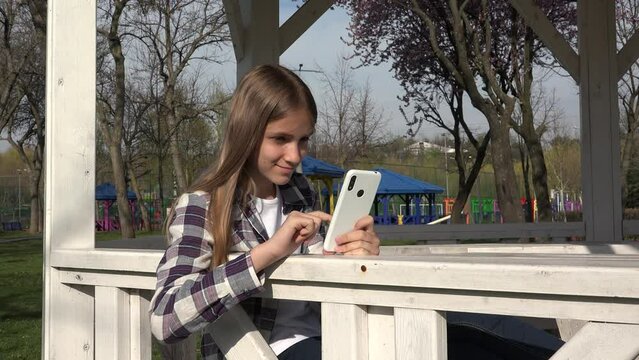 Young Child Browsing Internet on Smart Phone in Park, Adolescent Kid Playing Smartphone, Teenager Girl use Devices Outdoor 