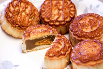 Whole mooncakes and one sliced mooncake showing delicious lotus seed paste and egg yolk filling, mooncakes are a custom treat for Mid-Autumn Festival in Chinese culture