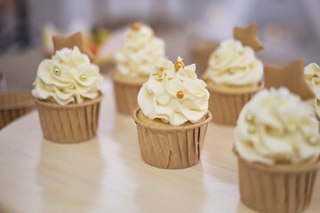 Tasty cupcakes on wooden board. Decorating a white cake with cream from the pastry bag.