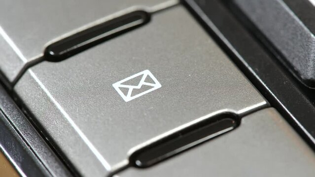 Man pressing the e-mail button, finger pushing the email client shortcut key with an envelope icon symbol on an office keyboard, sending e mails, messages, online communication simple abstract concept