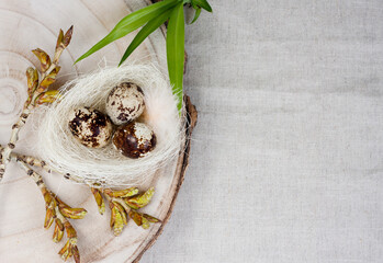 Still life. Small nest with quail eggs stands on stand made of cut wood. Postcard Happy Easter. On light background. Place for text. Top view. Flat lay.