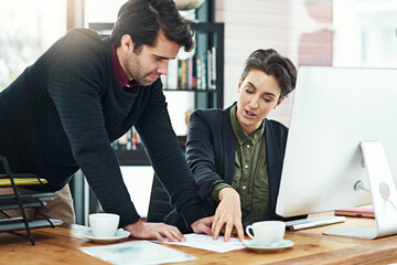 This is what we need to focus on now. Cropped shot of two businesspeople discussing work at a desk in their office.