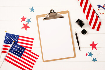 Blank paper on craft clipboard for mockup design with USA flag and ink top view flat lay