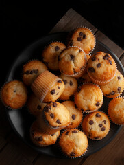 Dark food macro photography, lay flat or top view of vanilla cupcakes with chocolate chips, concept of homemade desserts. vertical