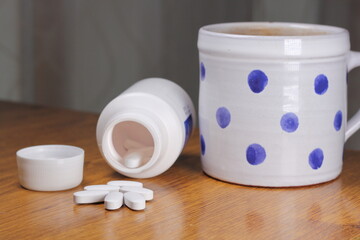 Anti-Radiation Pills, Iodine tablets, tablets for radiation protection on the wooden table with a white medical jar and blue polka dot mug