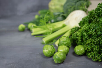 Green vegetables and herbs assortment on a grey stone background. Copy space.