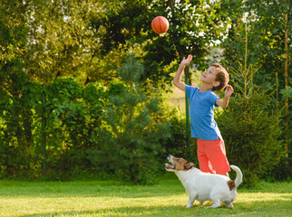 Kid and dog are playing leisure basketball game outdoors on summer day