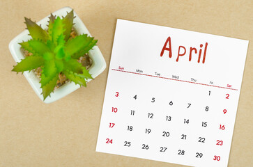 April 2022 calendar with plant pot on brown paper background.