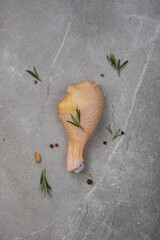Raw chicken meat with spices on gray marble.