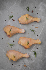 Raw chicken meat with spices on gray marble.
