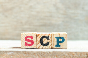 Alphabet letter block in word SCP (Abbreviation of .Service control point, Supply chain planning, Standard corporate protocol or Salary continuation plan) on wood background