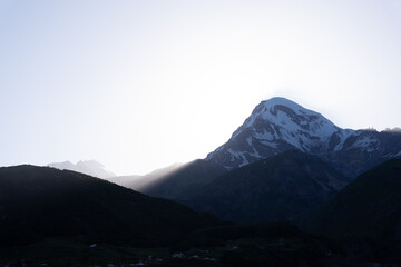 the kazbegi mountain ranges in georgia are green and have a clear sky above them