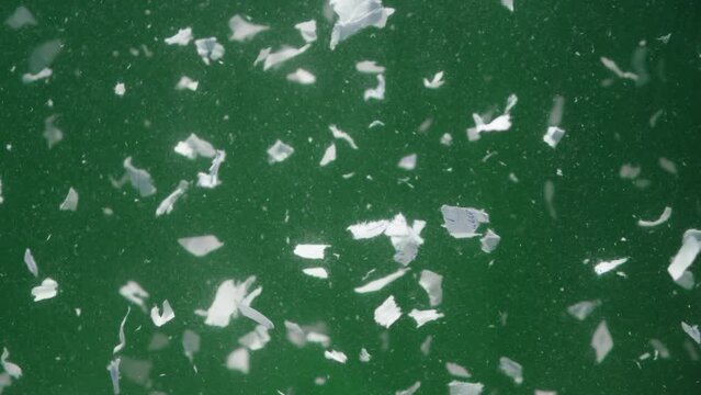 Video of paper scraps underwater on green background