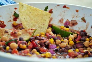 Fresh black bean and corn dip in a large serving bowl with tortilla chips and lime