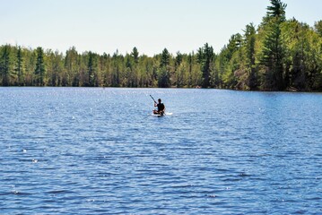 teen girl paddle boarding in the middle of a lake upper peninsula michigan - obrazy, fototapety, plakaty