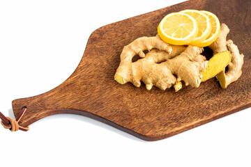 Ginger roots with chopped lemon slices lie on a cutting kitchen board, white background.