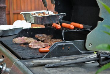 Hotdogs and steak on the grill at a backyard cookout
