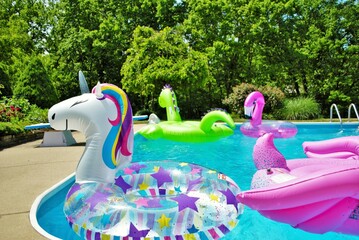 a lot of inflatables floating in a backyard swimming pool