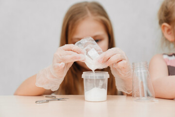 a cute little girl in protective gloves conduct an experiments at home 