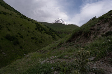 The mountain ranges of Georgia, Kazbegi, where two mountains form a triangular shape and above them a mountain spice that is covered with white snow