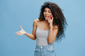 ONLINE CALL AD CONCEPT. Screaming beautiful curly Latin lady hold pink smartphone in hand, quarrel...