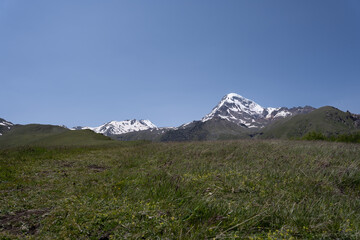 The mountain ranges of Georgia, Kazbegi, where two mountains form a triangular shape and above them a mountain spice that is covered with white snow