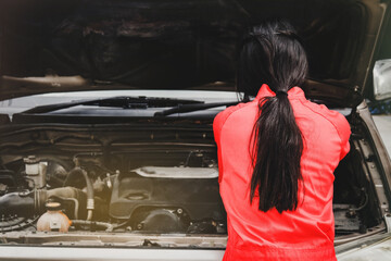 Back view, professional Asian female mechanic in red uniform checks and fixes diesel pickup truck :...