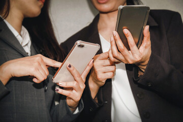Two business women use their phones to point out and compare how internet speeds affect their daily activities with mutual interest.