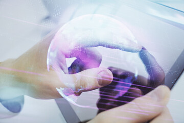 Double exposure of man's hands holding and using a digital device and tech theme hologram drawing....
