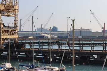 SAVONA, ITALY - February 12, 2022 - The port of Savona in the heart of the city on the italian riviera. Some old  container lifter near the new area. Beautiful small boats parked.