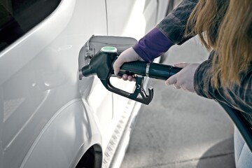 Unrecognizable woman putting petrol in her car. Horizontal image with selective focus.