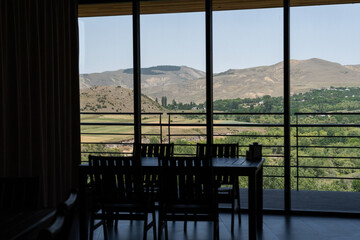 a table in a cafe where there is a large glazed window which is just a silhouette ai which can see a number of Georgian mountain landscapes