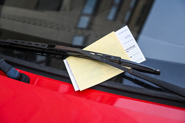 Car with penalty charge notices on the street. Ticket fine on windscreen for parking violation. Parking notice enclosed. - obrazy, fototapety, plakaty