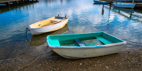 Obraz premium Weathered dinghies tied to the ropes at the pier. Idyllic seascape with empty boats.