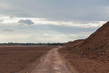 A red dirt road beside a newly dug clay dam.