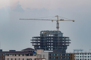 Construction cranes on concrete buildings as the sky nears dark.