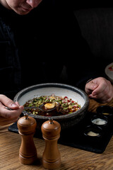 Young man is eating okroshka in a restaurant, hands are visible, dusk light, soft shadows, ad photo