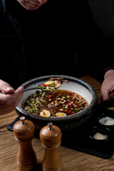 Eating soup in a modern cuisine restaurant, dark lights, black background, no face