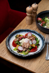Canned tuna salad with poached egg on a beautiful stone dish in a dark restaurant