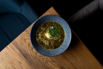 Fresh sorrel soup on a wooden table of a dark restaurant