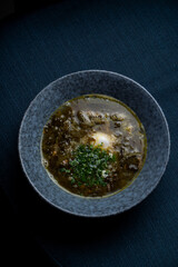 Fresh sorrel soup on a wooden table of a dark restaurant
